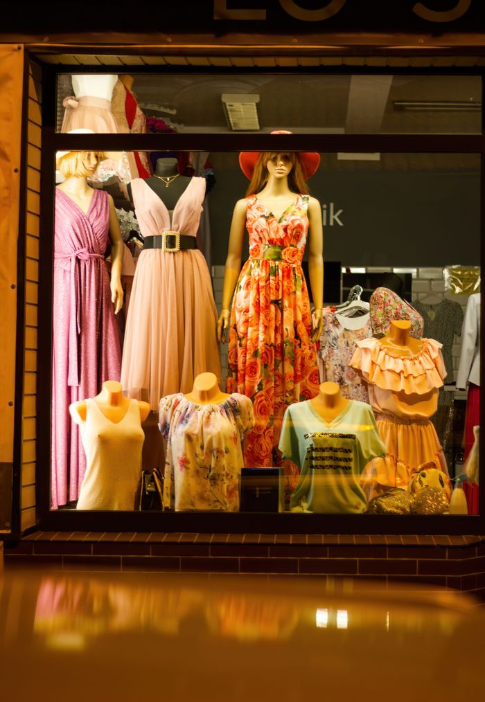Stylish window display with elegant dresses and mannequins under warm lighting.