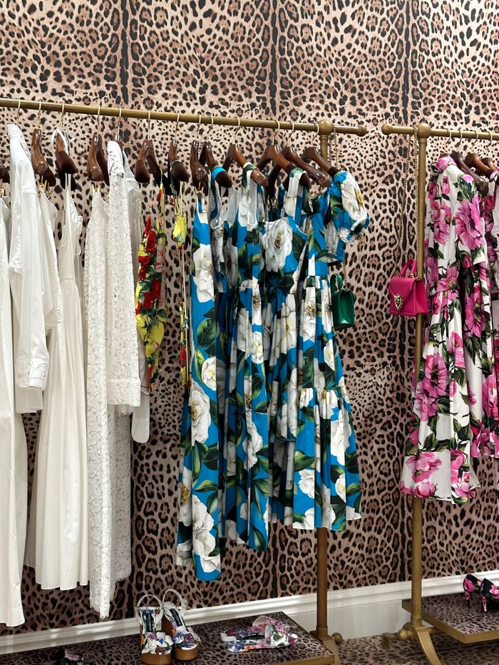 Colorful and elegant dresses displayed on a leopard print backdrop in a stylish boutique.