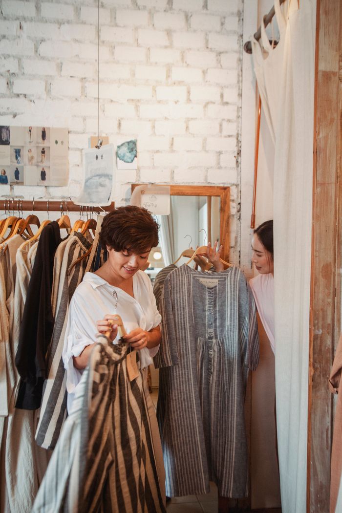 Crafting Captivating Headlines: Your awesome post title goes here Positive young ethnic female customer giving various clothes to friend trying on dresses in fitting room of modern store